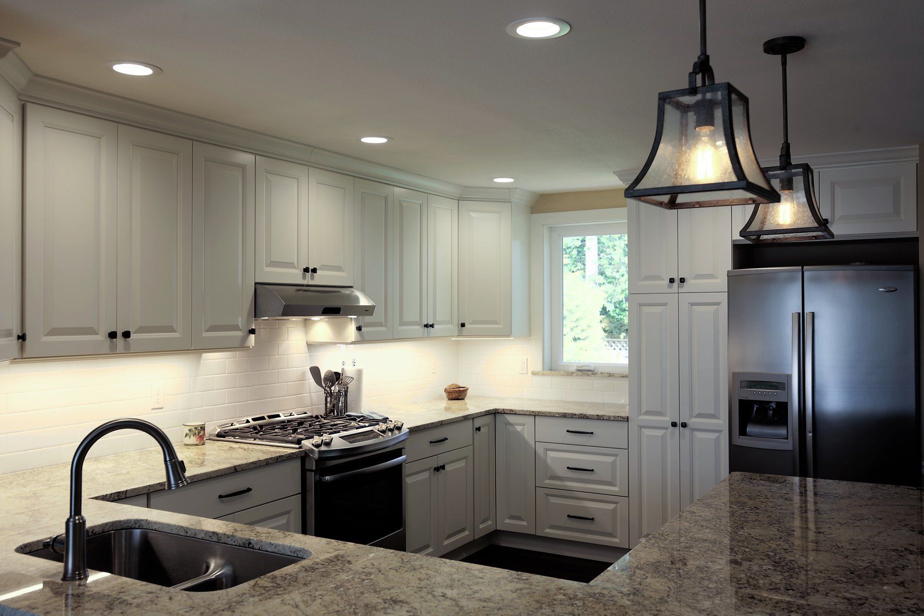 A kitchen with white cabinets and a stainless steel refrigerator.