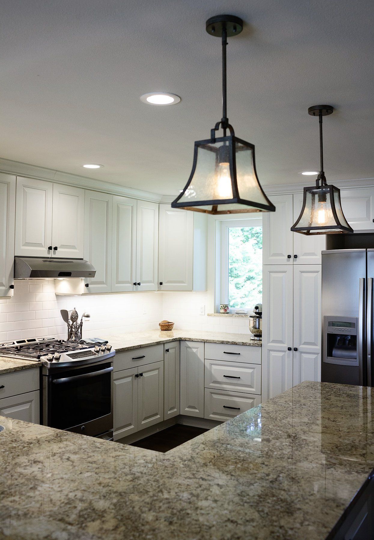 A kitchen with white cabinets and granite counter tops.