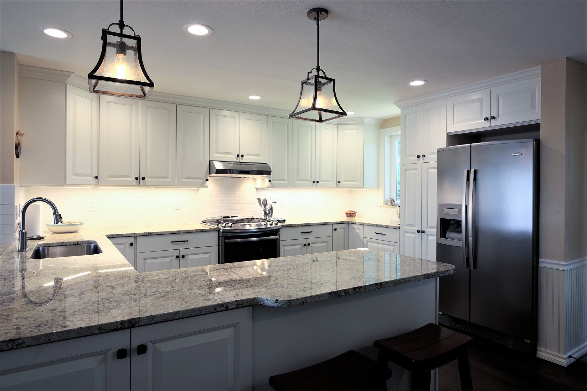 A kitchen with white cabinets and granite counter tops.