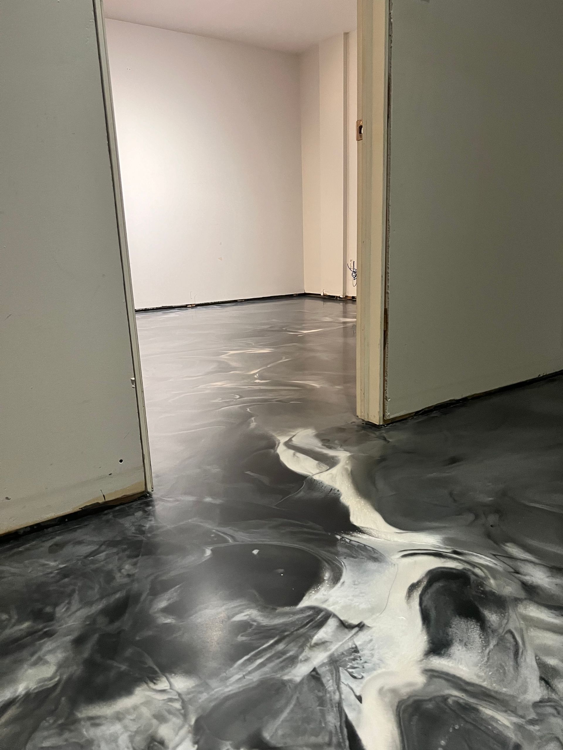 Une pièce avec un sol en marbre et une porte menant à une autre pièce.