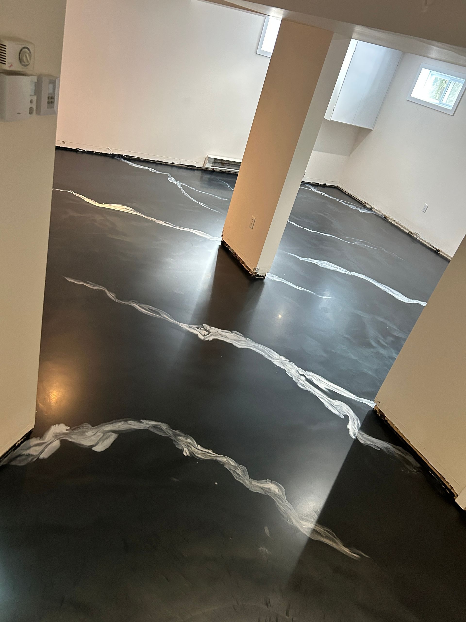 Une pièce avec un sol noir et des lignes blanches dessus