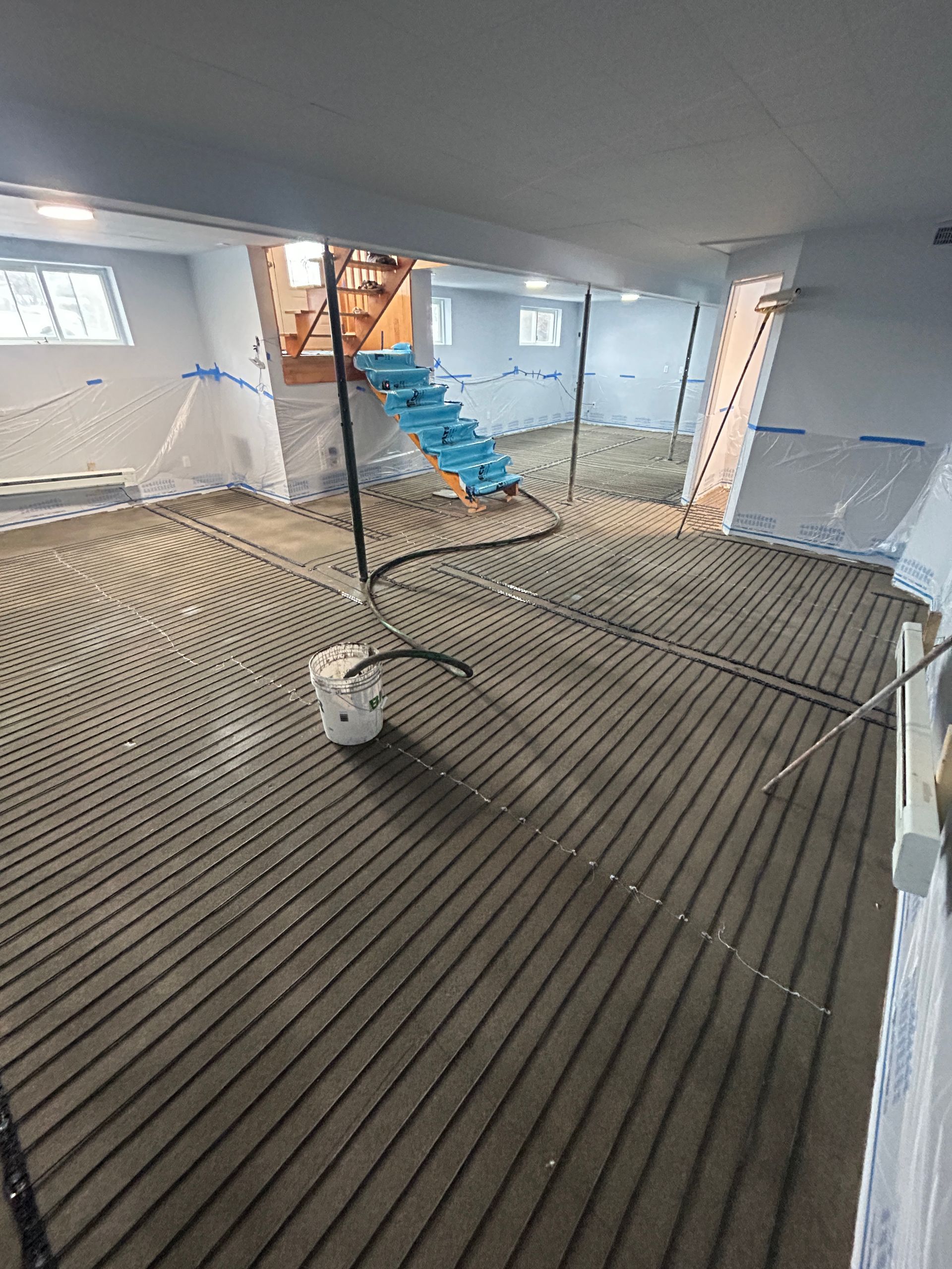 Un aspirateur est posé sur le sol d'un sous-sol en construction.