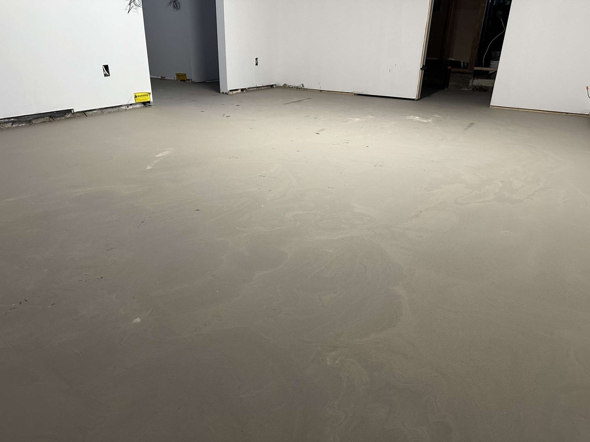 Une pièce avec un sol en béton et des murs blancs.