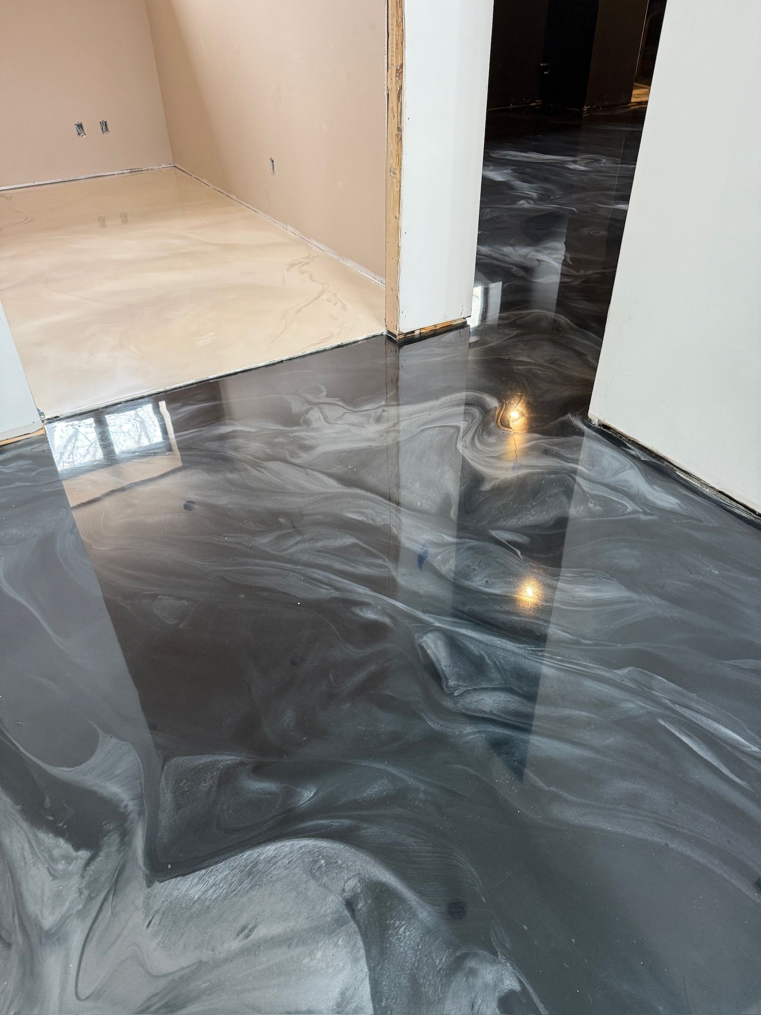 Sol époxy métallique brillant dans une pièce aux murs clairs ; transition vers un sol plus clair.