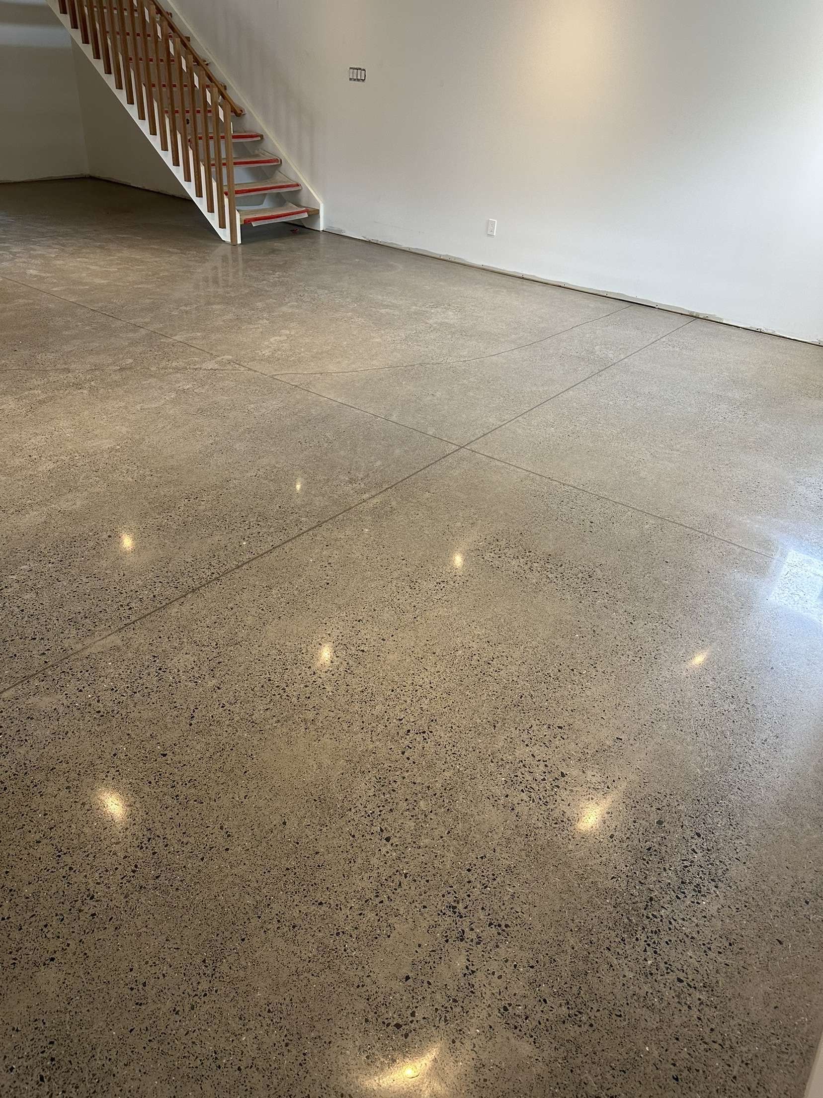 Sol en béton poli dans une grande pièce vide, avec des escaliers en arrière-plan.