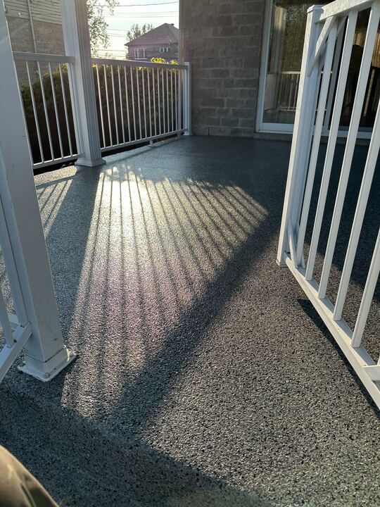 Une personne se tient sur un porche avec une balustrade blanche.