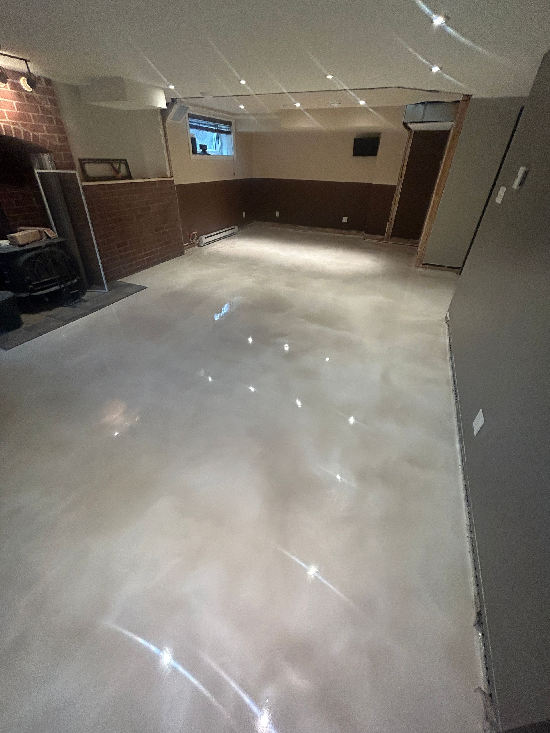 Une grande pièce avec un sol en béton brillant et une cheminée.