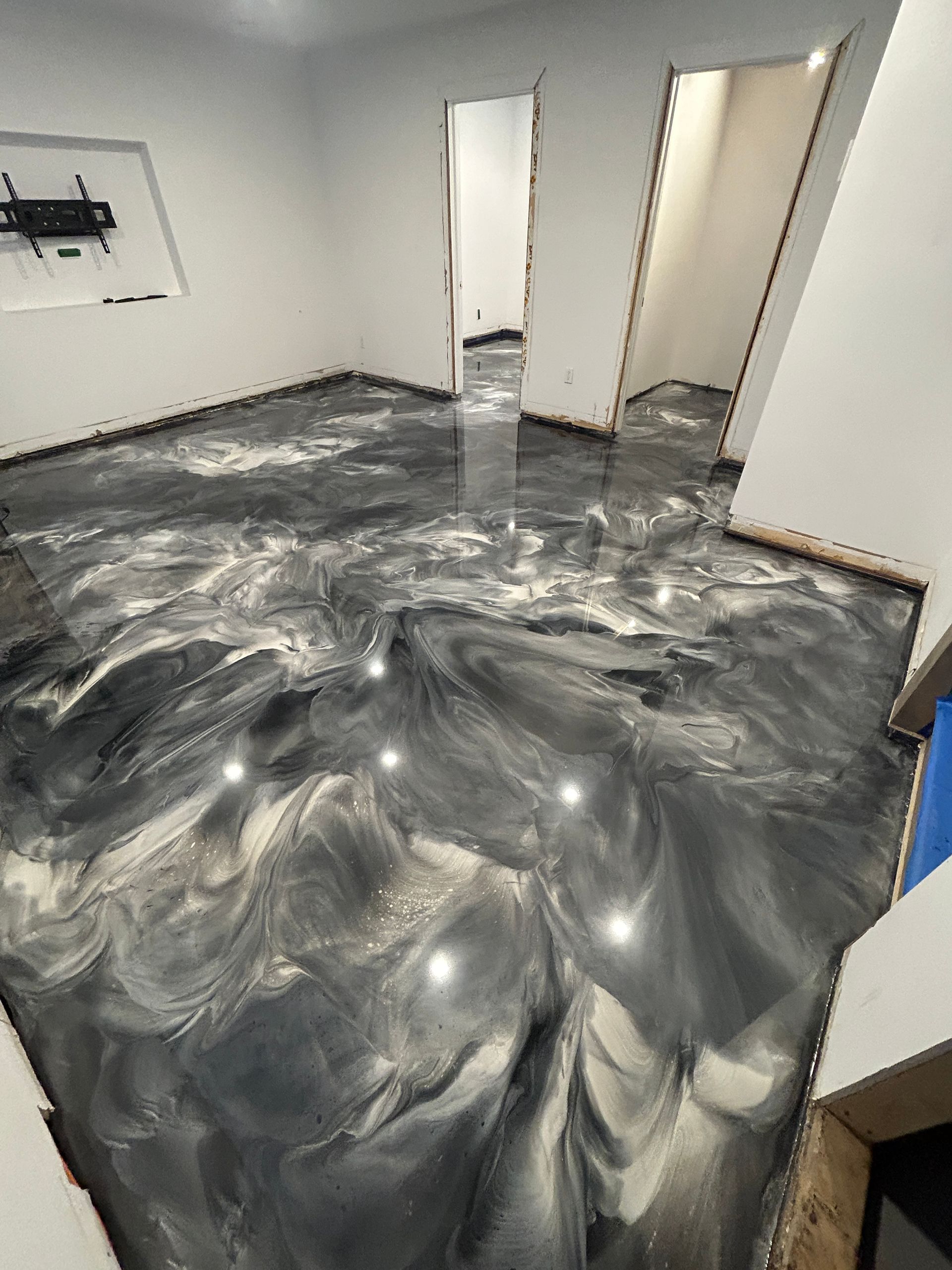 Une pièce avec un sol métallique brillant et une télévision fixée au mur.