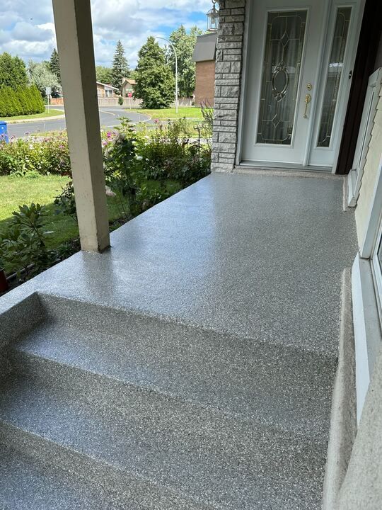 Un porche avec des escaliers qui y mènent et une porte.