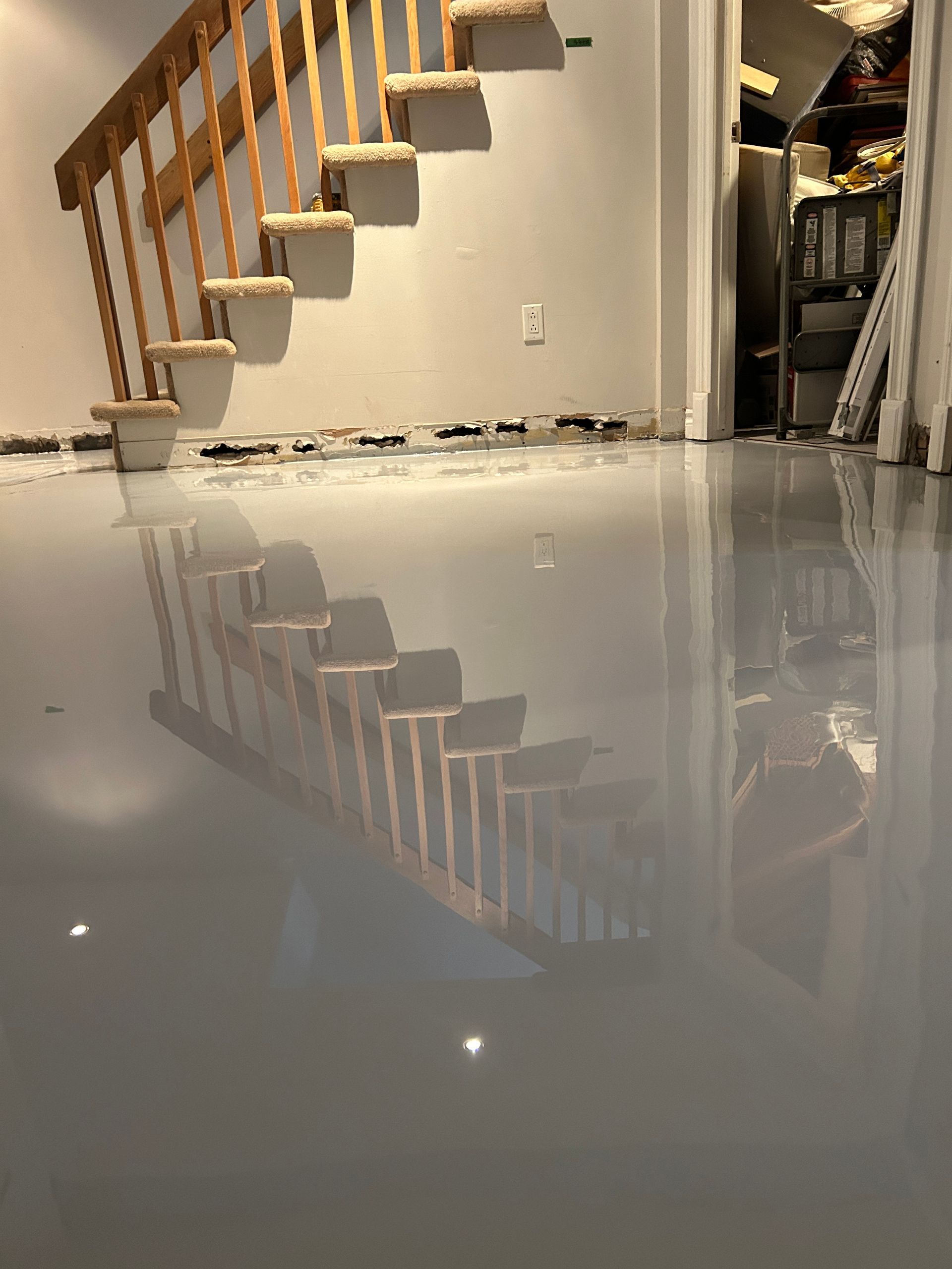 Un sous-sol avec un escalier et un reflet de l'escalier dans le sol.