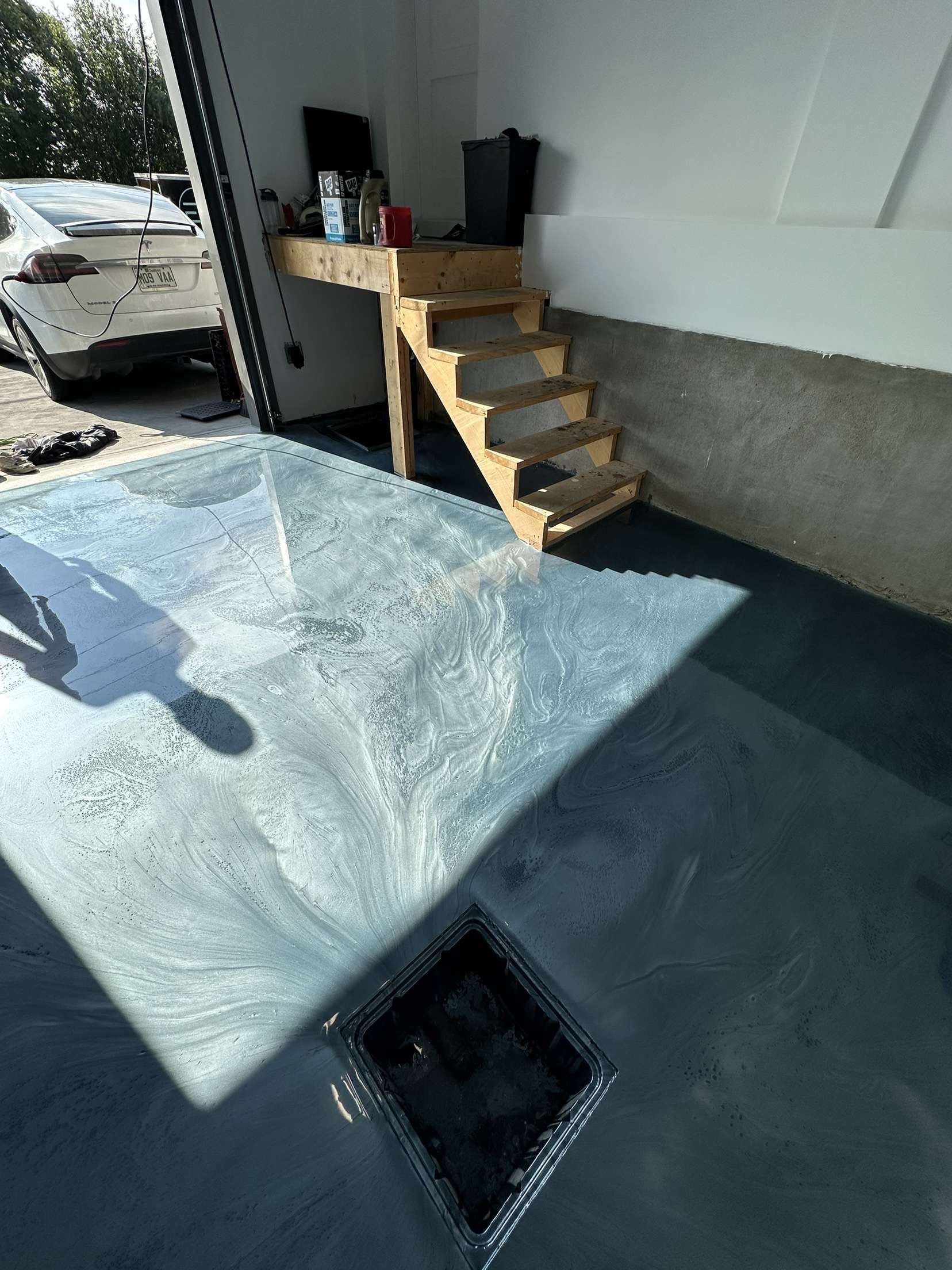 Une table en verre dans un garage avec des escaliers et une voiture en arrière-plan.