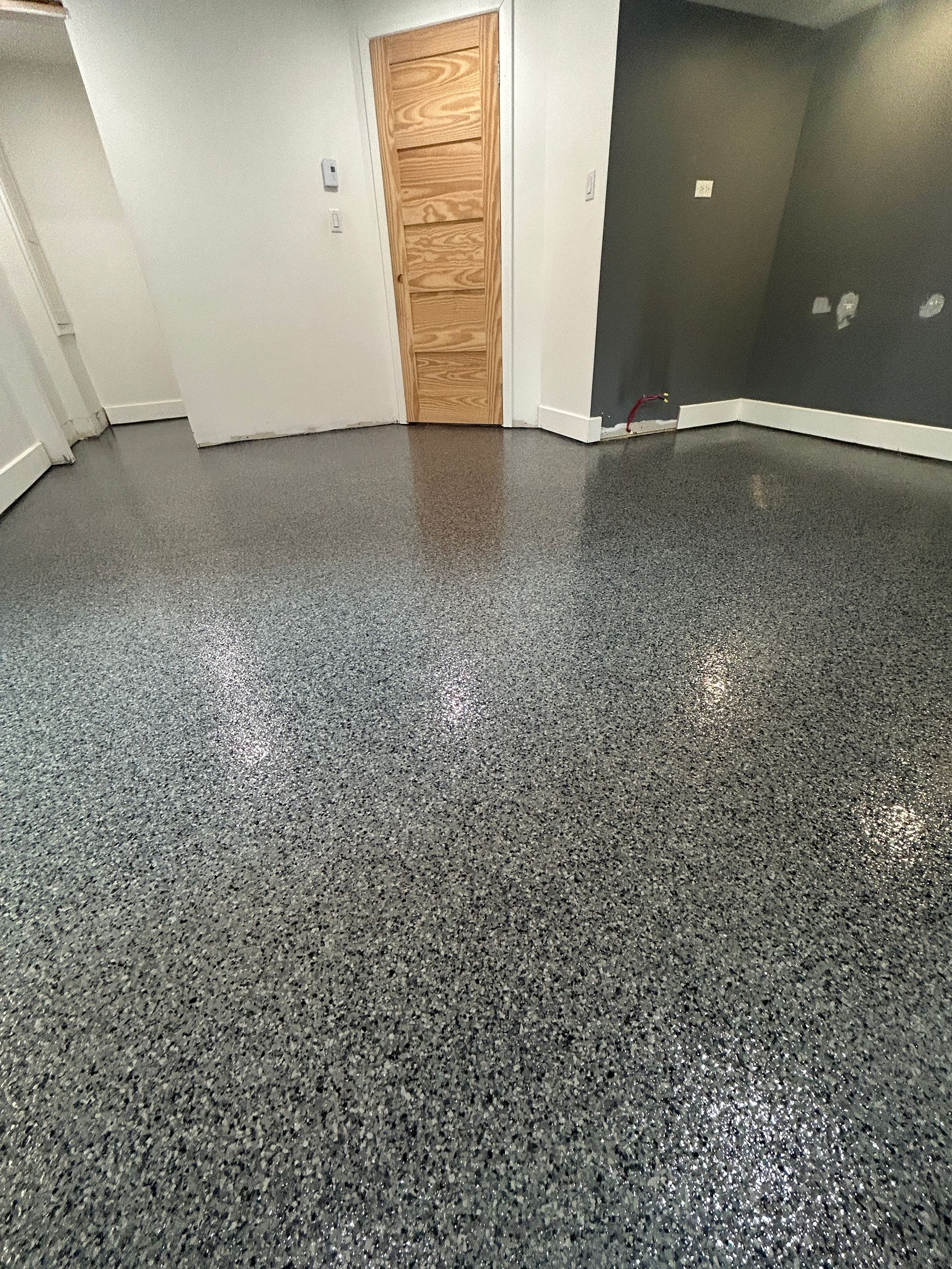Une pièce avec un sol gris et une porte en bois.