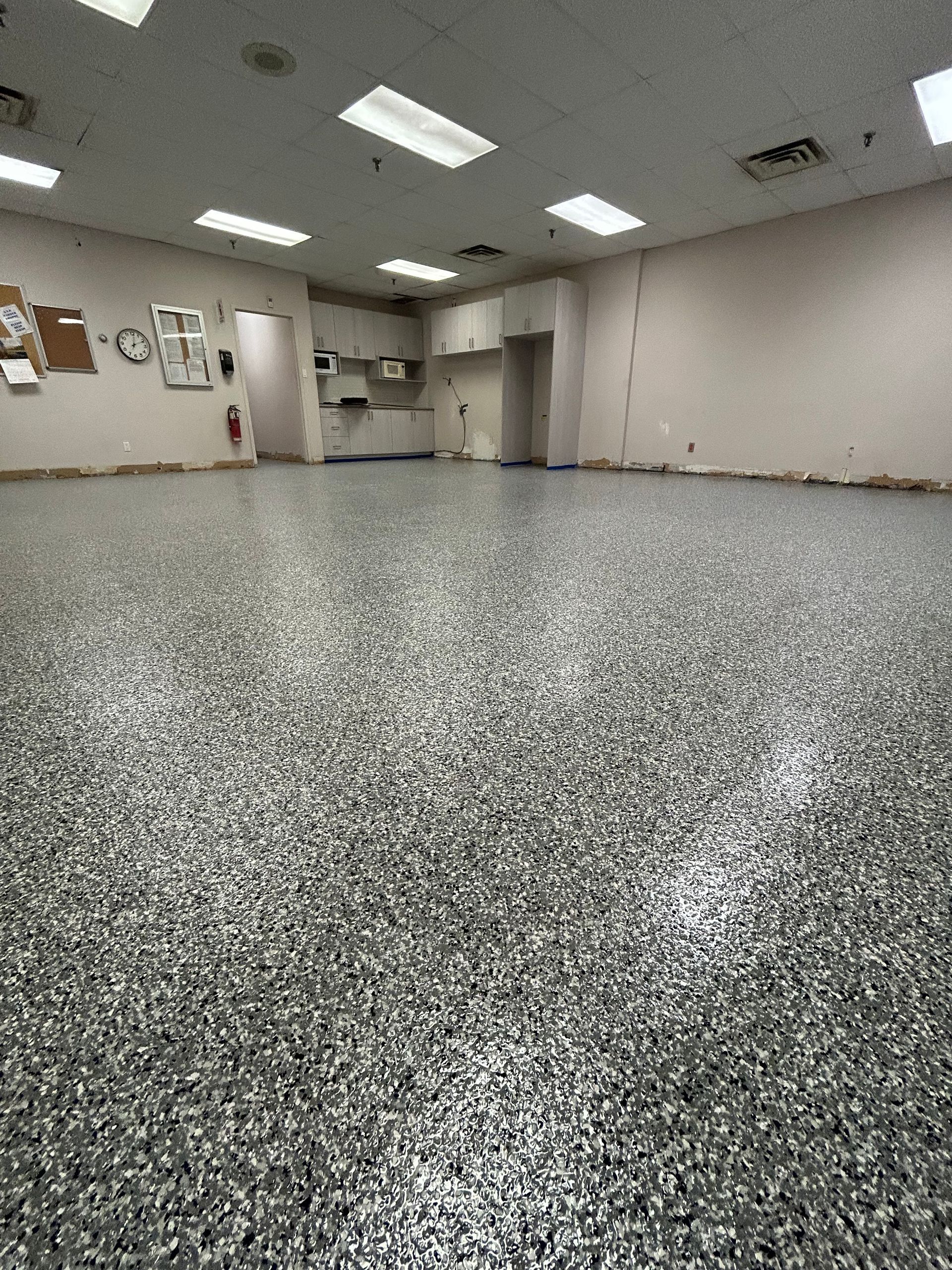 Une grande pièce avec un sol gris et des murs blancs.