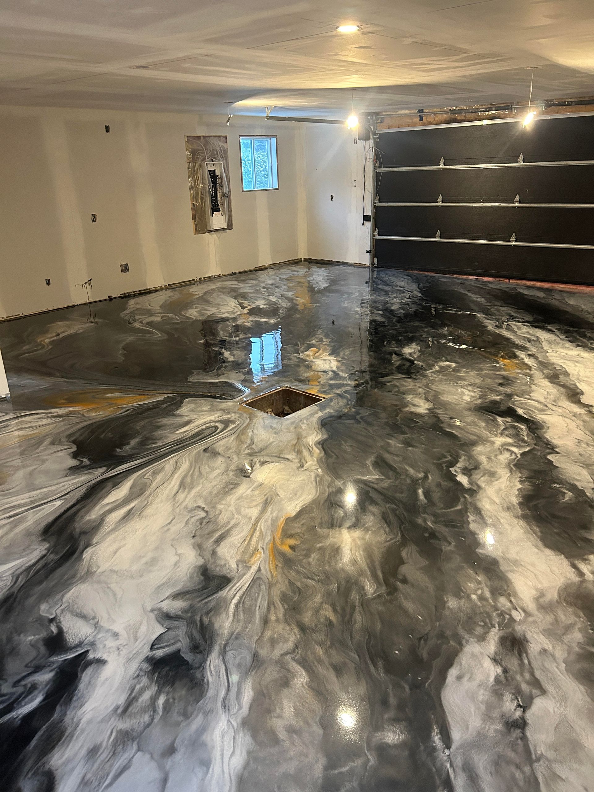 Un garage avec un sol en époxy noir et blanc et une porte de garage.