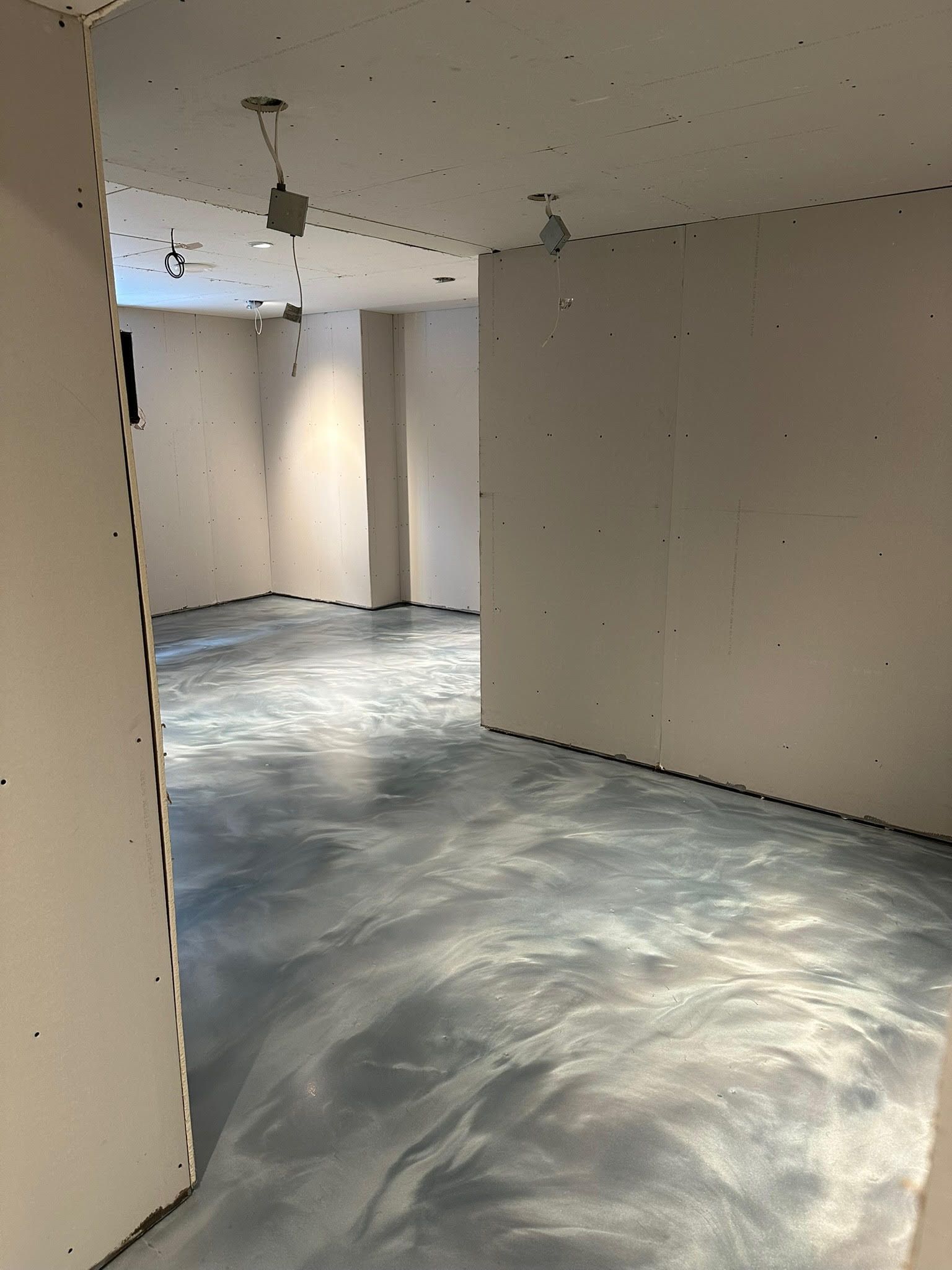 Une grande pièce avec un sol en béton brillant et une cheminée.