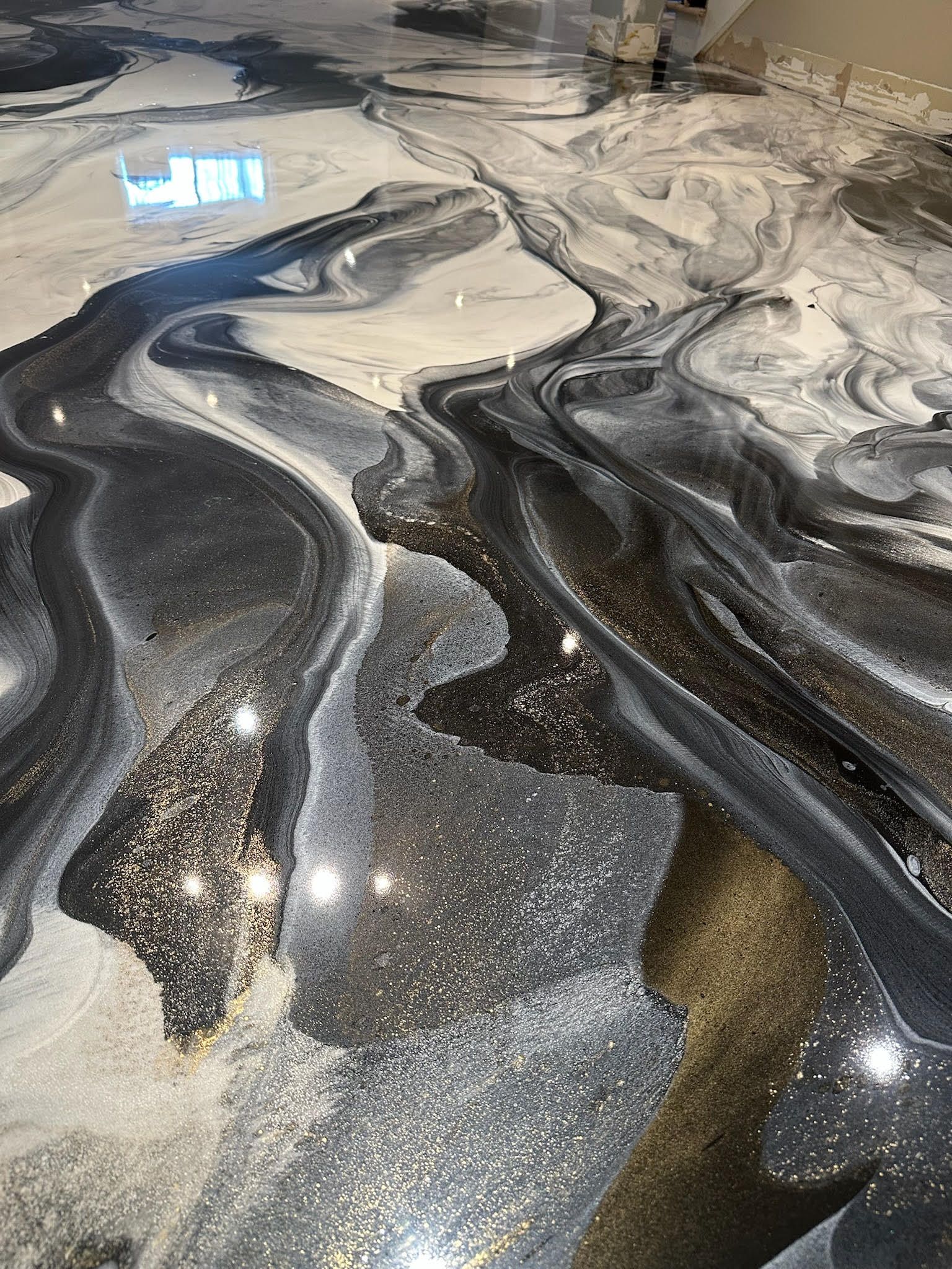 Un garage avec un sol en époxy noir et blanc et une porte de garage.