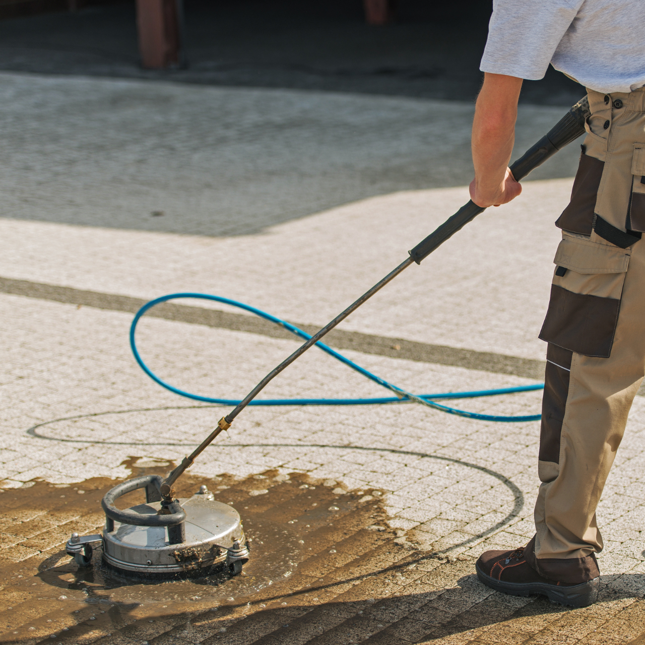 A man is using a pressure washer to clean a patio