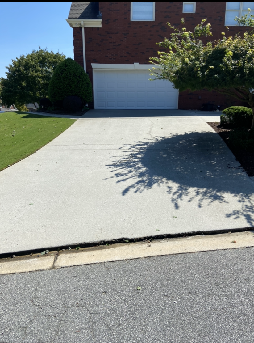 A pressure cleaned driveway leading to a brick house with a white garage door