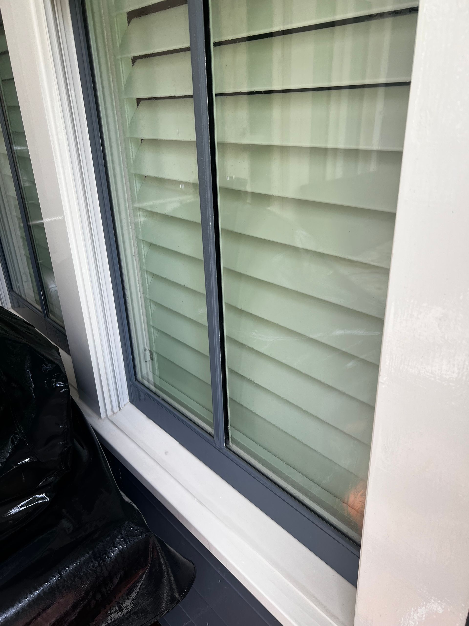 A close up of a pressure cleaned window with blinds on it