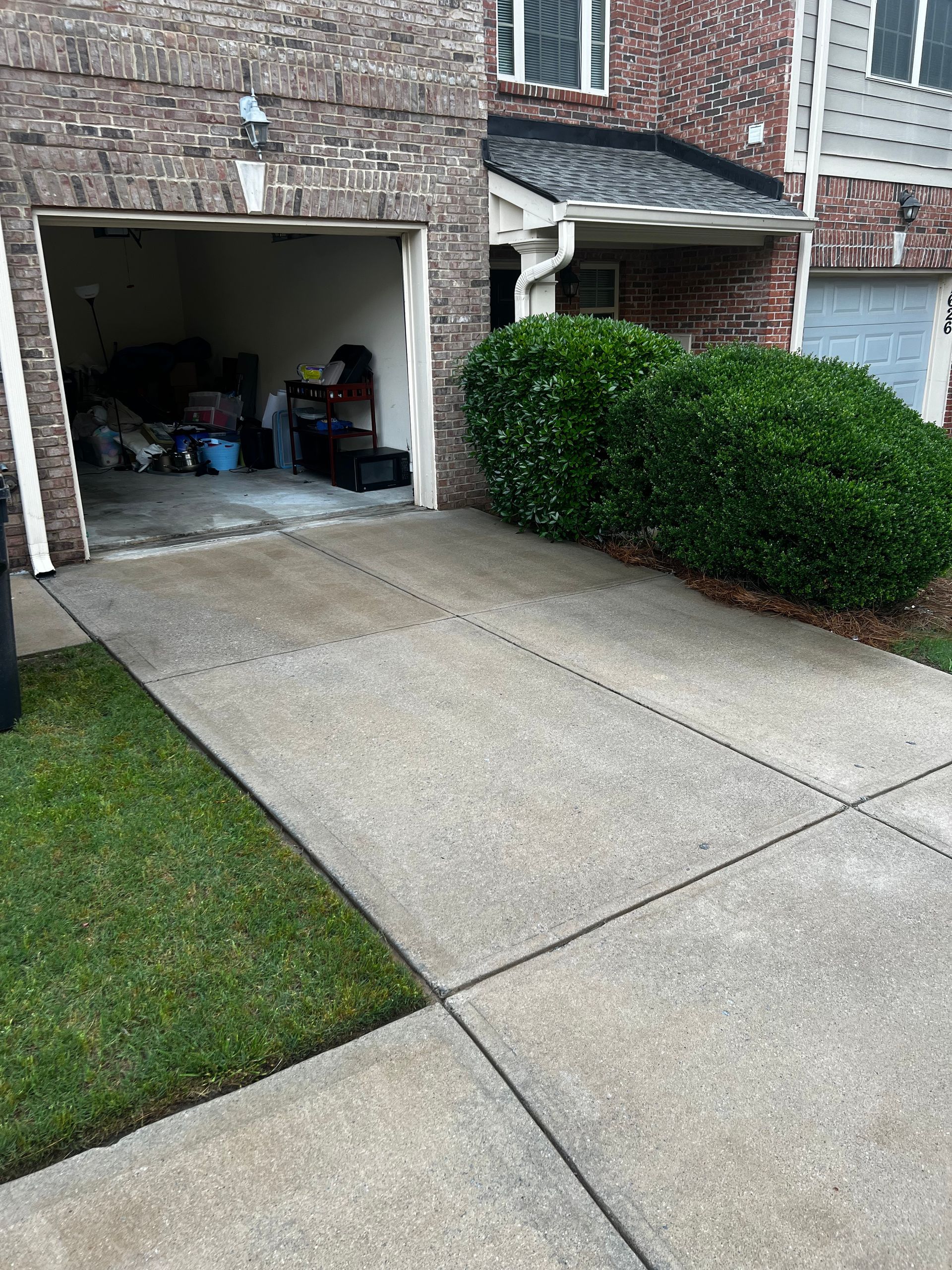 A driveway leading to a garage with a brick building in the background.