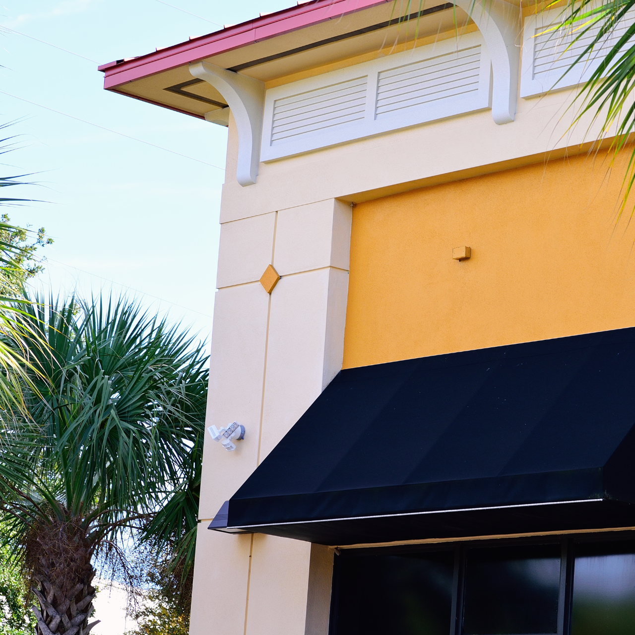 A yellow building with a black awning on the side