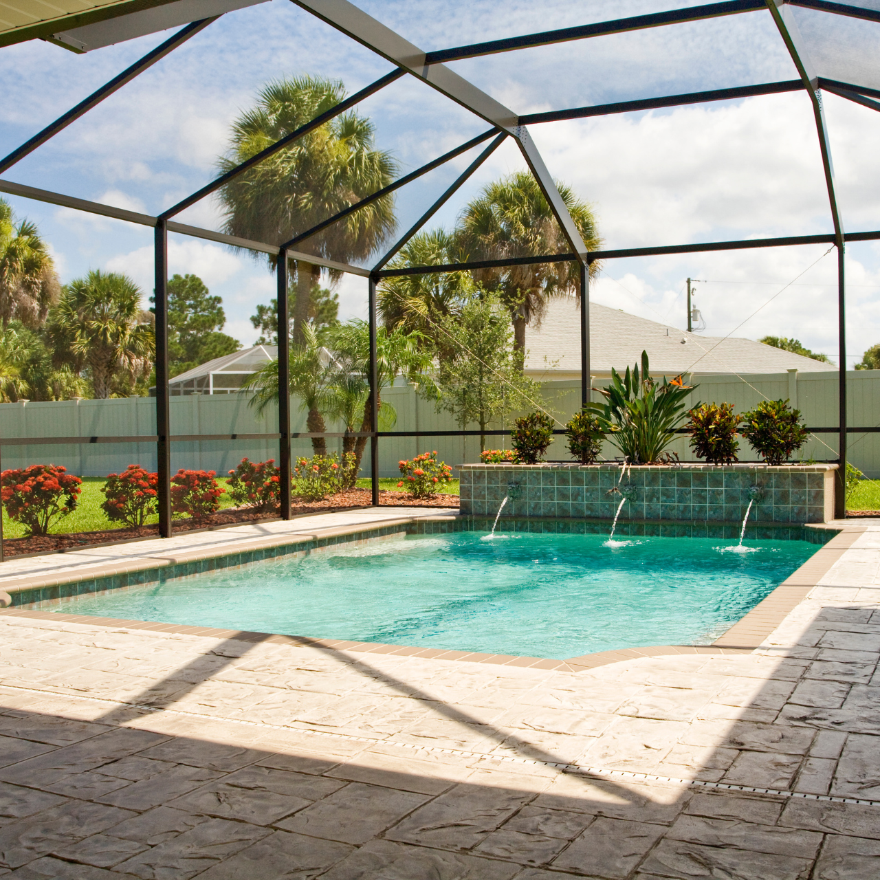 A swimming pool under a screened in area with palm trees in the background