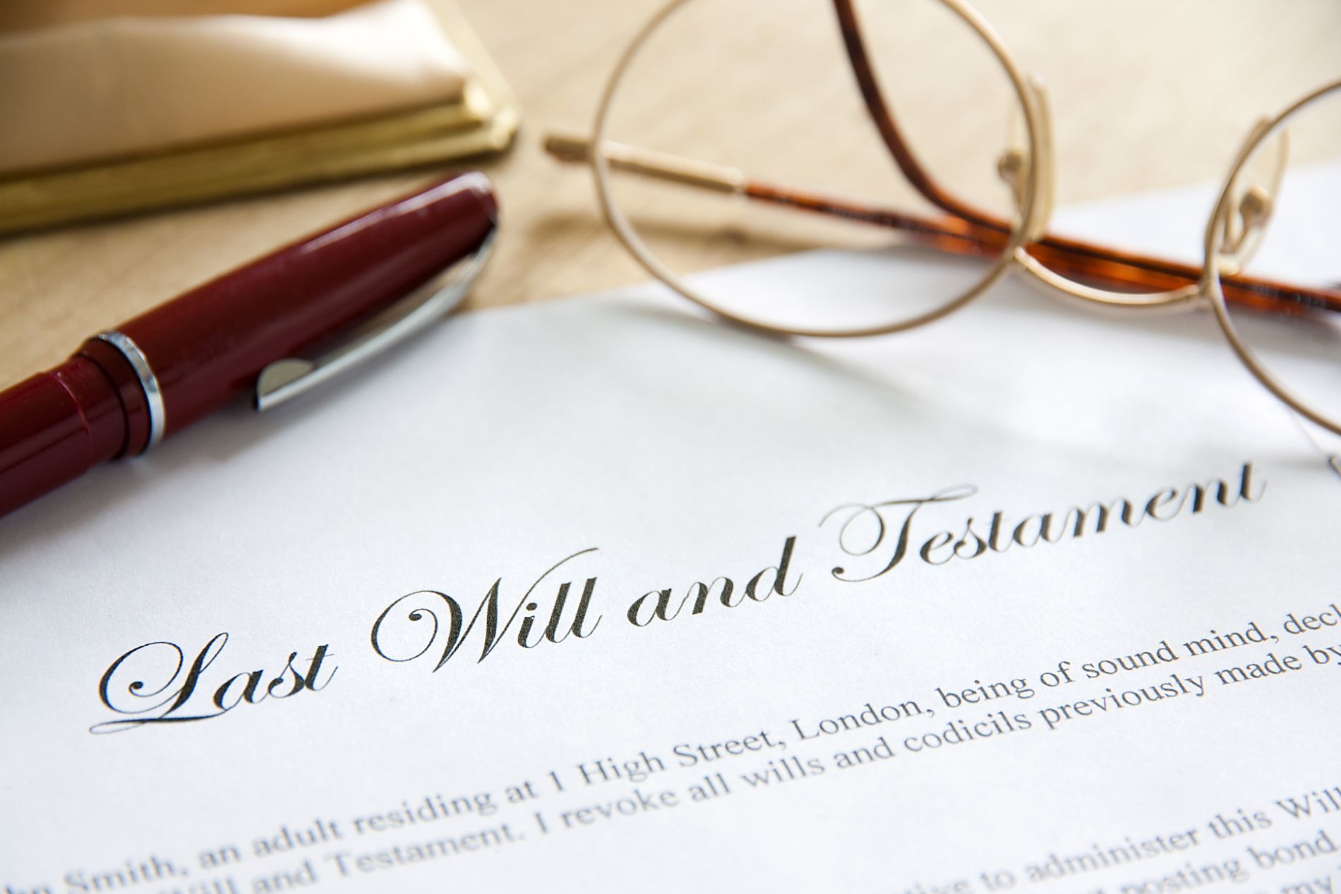 a close up of a last will with a pen and a pair of spectacles resting on top of it