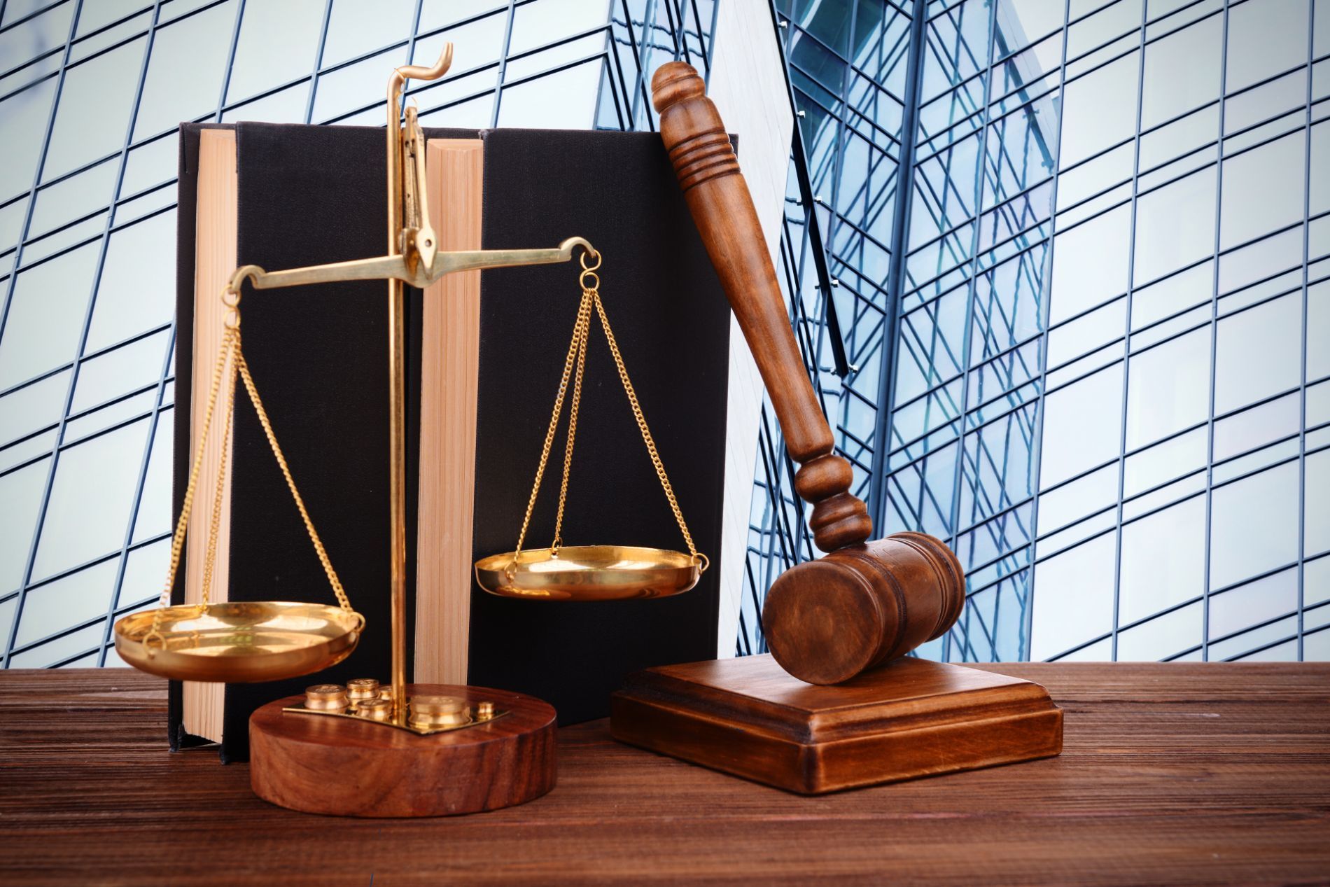 A statuette of the scales of Justice next to a gavel resting vertically against a legal book