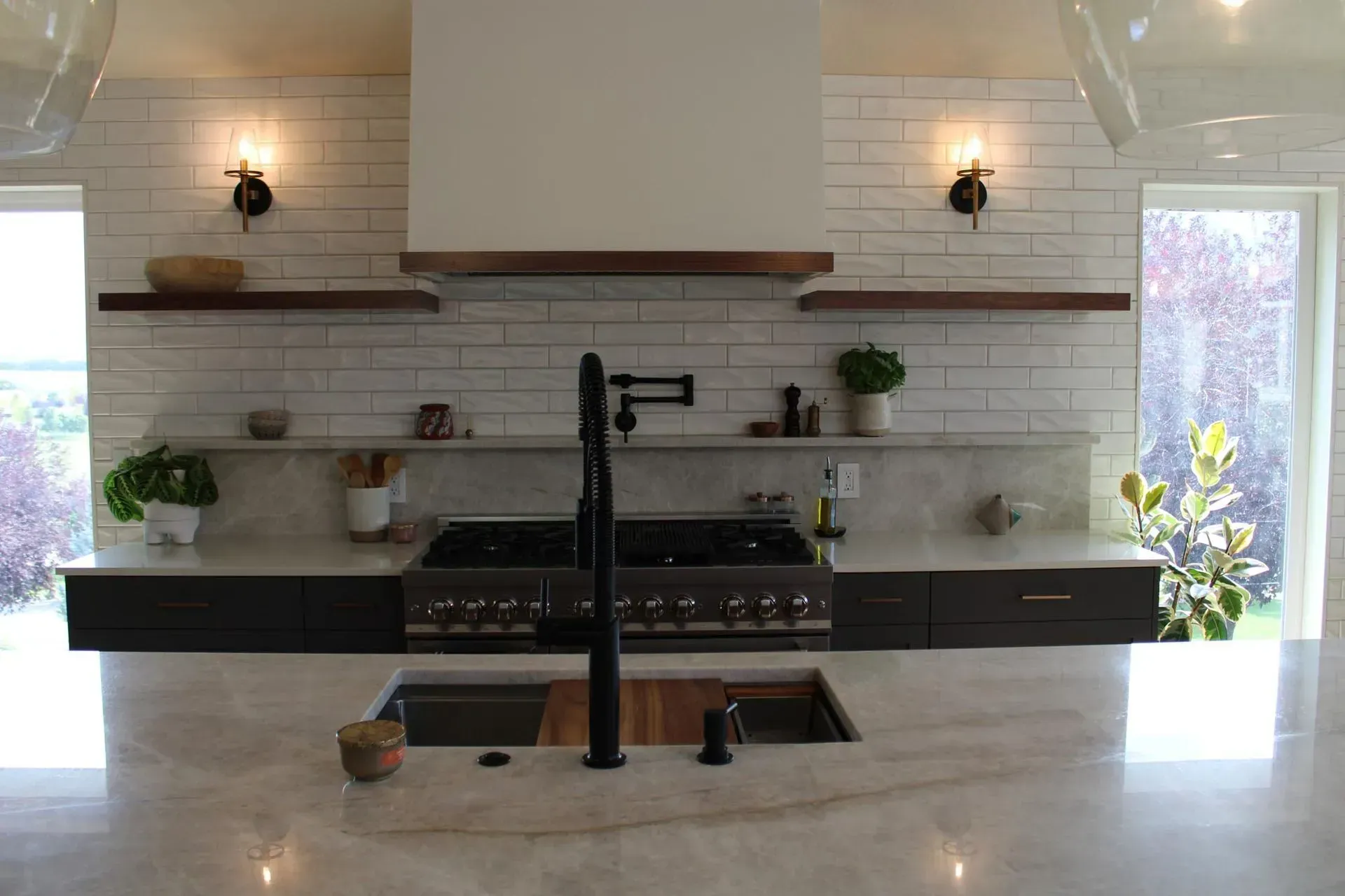 A kitchen with a sink , stove , and shelves.