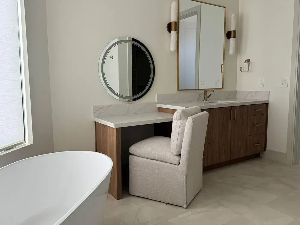 A bathroom with a sink , chair , mirror and tub.