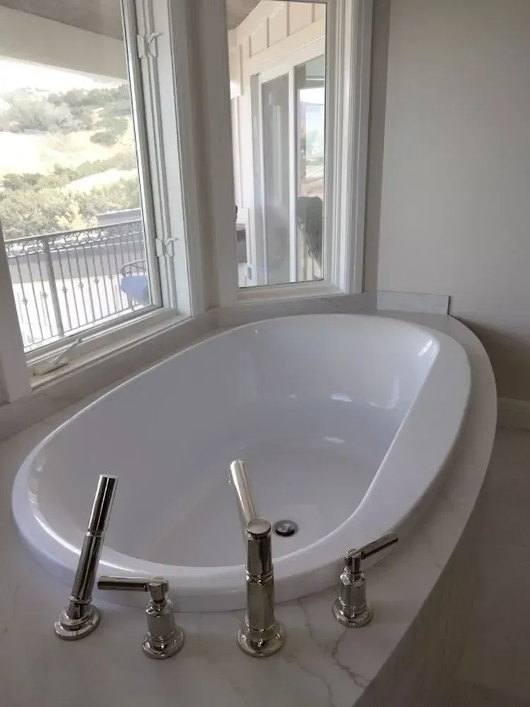 A white bathtub is sitting in a bathroom next to a window.