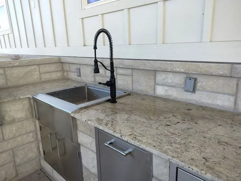 A kitchen with a stainless steel sink and granite counter tops.