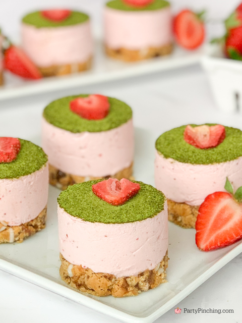 Strawberry Matcha Mousse Bites topped with a fresh strawberry slice, served on a base made from Sunbelt Bakery Strawberry Soft Baked Granola Bars, set against a pink background with text overlay.