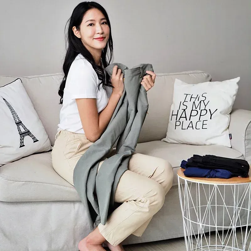 一位身穿白襯衫和黑褲子的女人站在牆前。