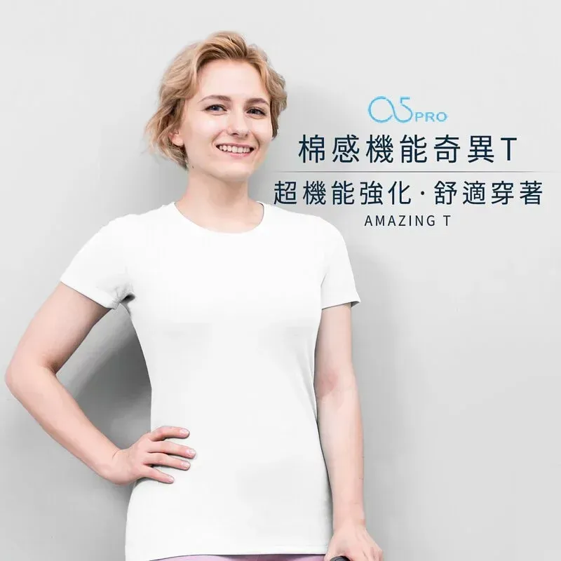 一位留著金色短髮的女子，身穿栗色襯衫和藏藍色褲子，站在一面灰色牆前。