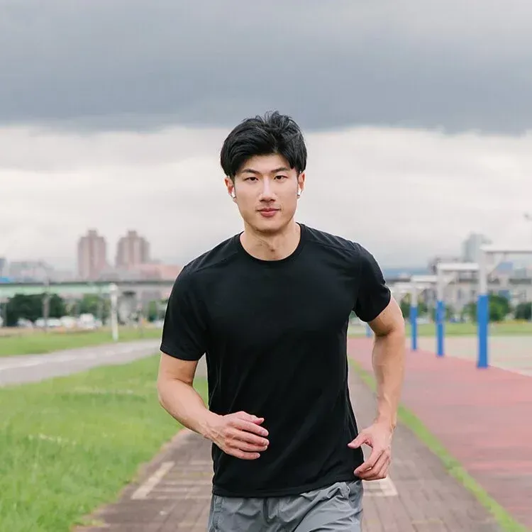 一名身穿黑色襯衫的男子正在跑道上跑步。