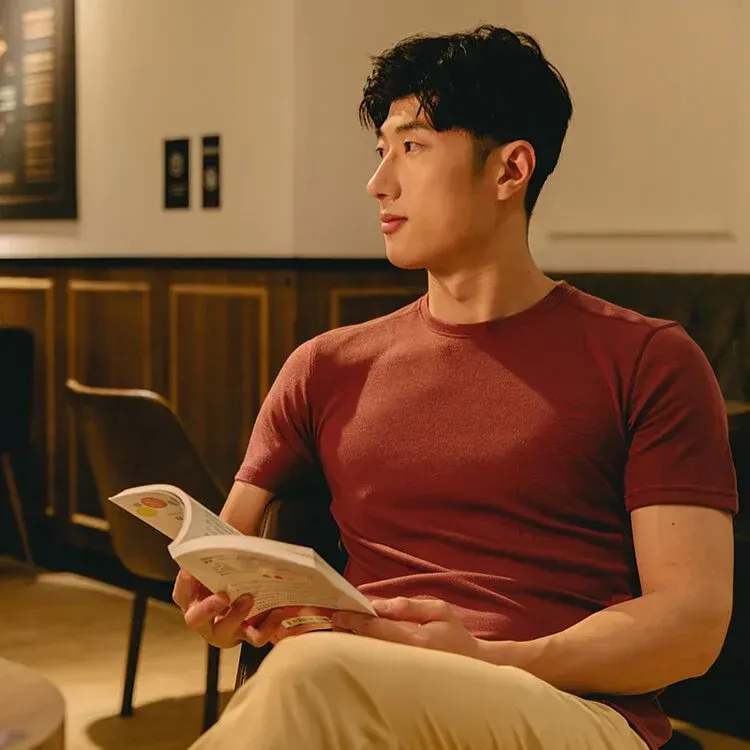 一位穿紅襯衫的男子坐在椅子上看書