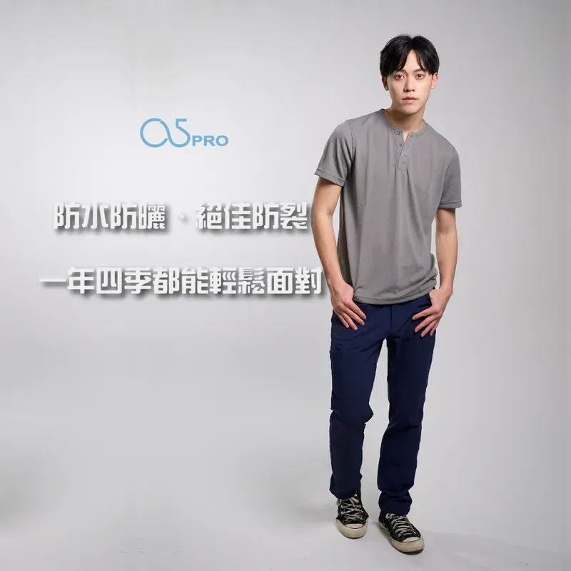 一名身穿灰色 T 恤和藍色褲子的男子站在那裡，雙手插在口袋裡。