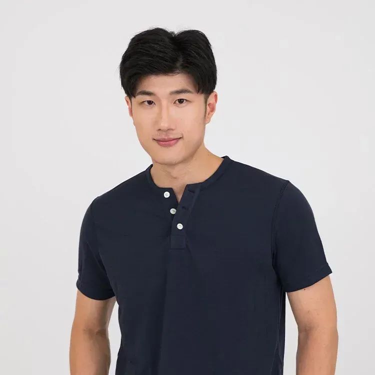 一名身穿藍色 T 恤的年輕男子站在白色背景上。
