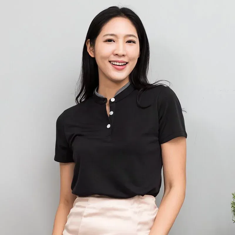 一位穿著黑色襯衫和粉紅色裙子的女子正微笑著。