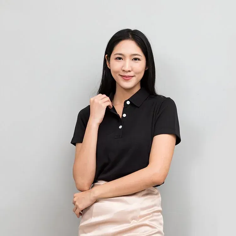 這位女子身穿一件黑色 Polo 衫和一條米色裙子。
