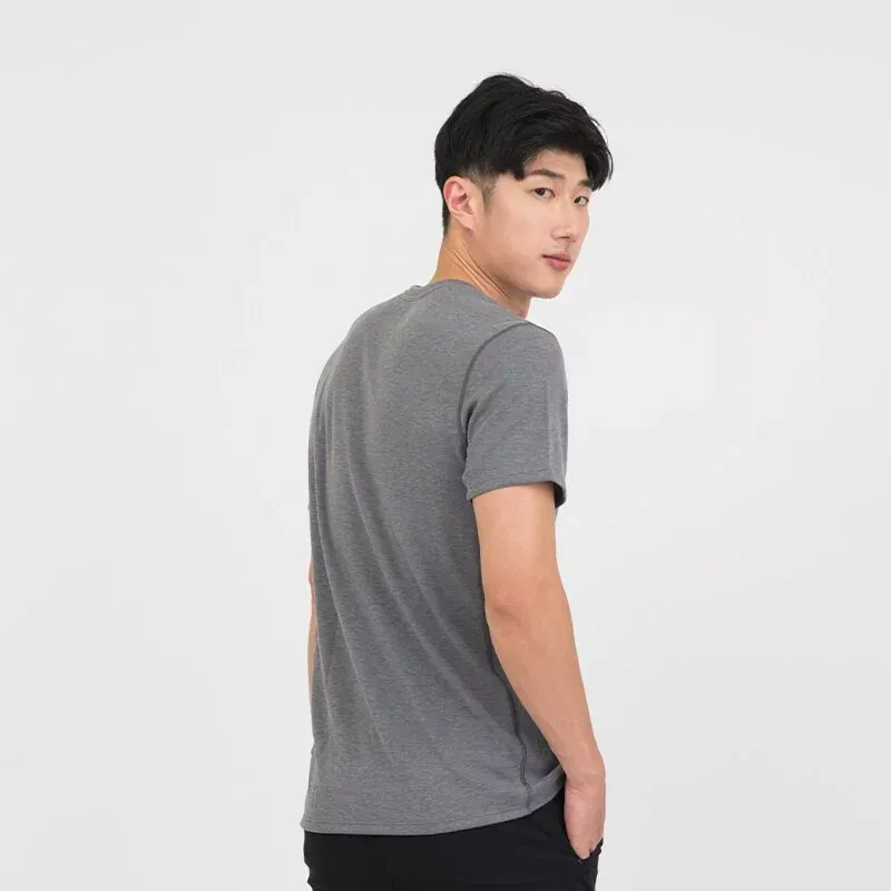 一名身穿黑色 T 恤和卡其褲的男子站在那裡，雙手插在口袋裡。