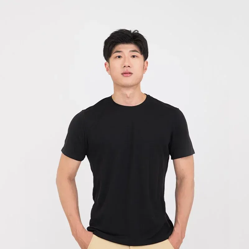 一名身穿黑色 T 恤和卡其褲的男子站在那裡，雙手插在口袋裡。
