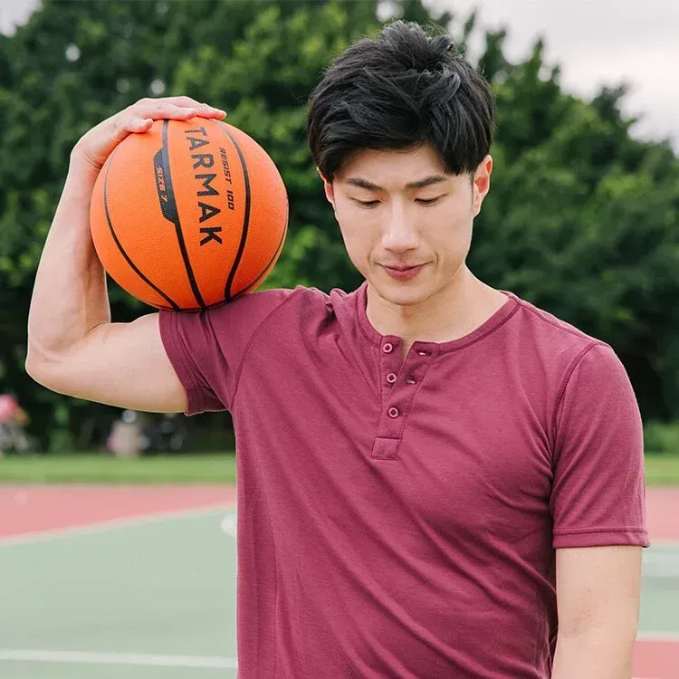 一名身穿栗色襯衫的男子肩上扛著一隻橘色籃球。