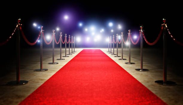 Red carpet runway with velvet ropes, spotlighting a glamorous event.