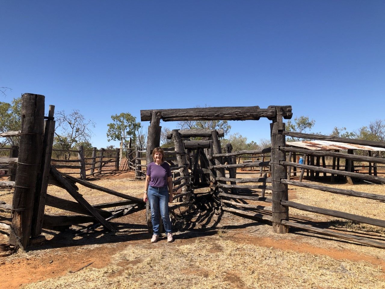A woman is standing in front of a wooden fence.