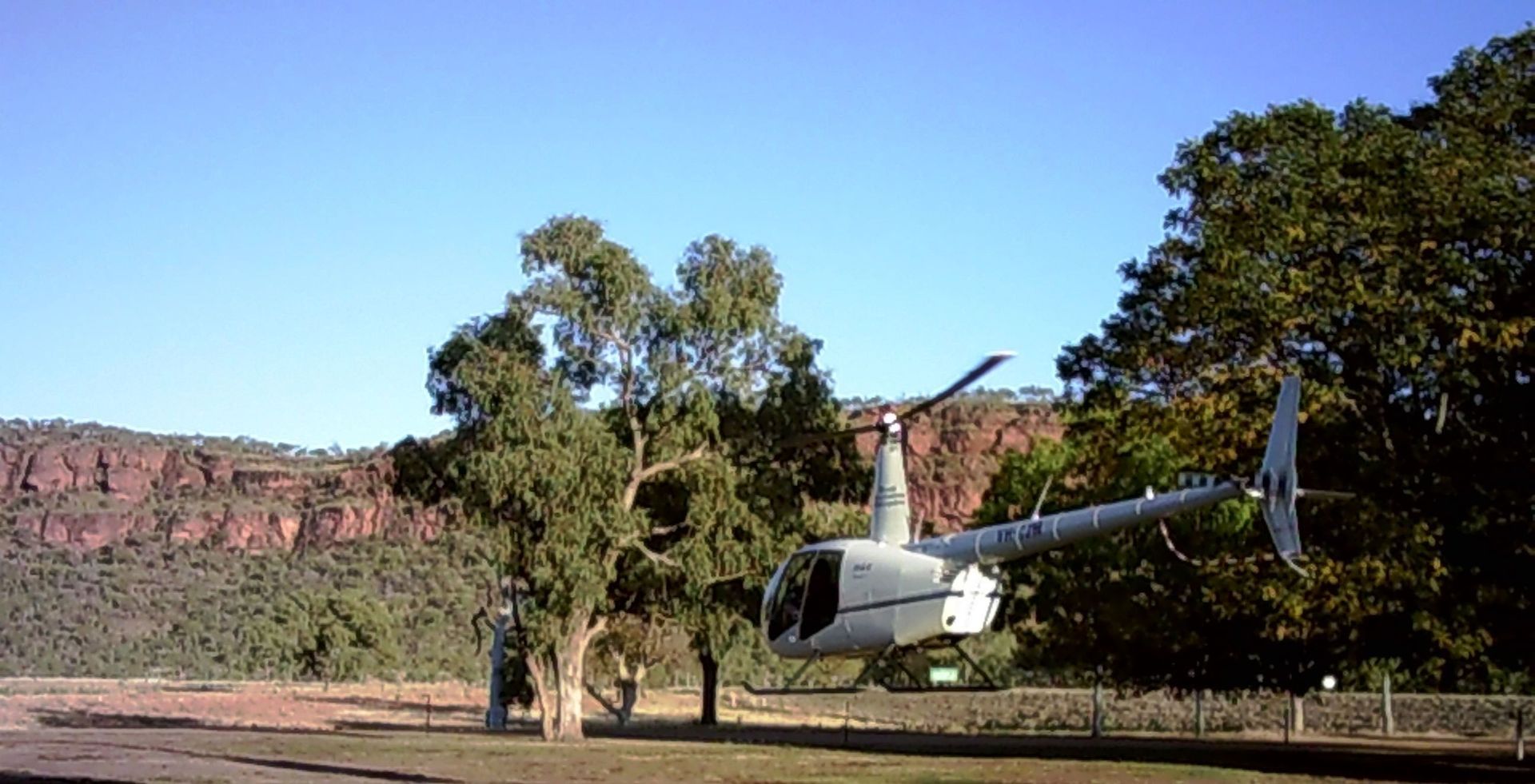 A helicopter is parked in a field with trees in the background