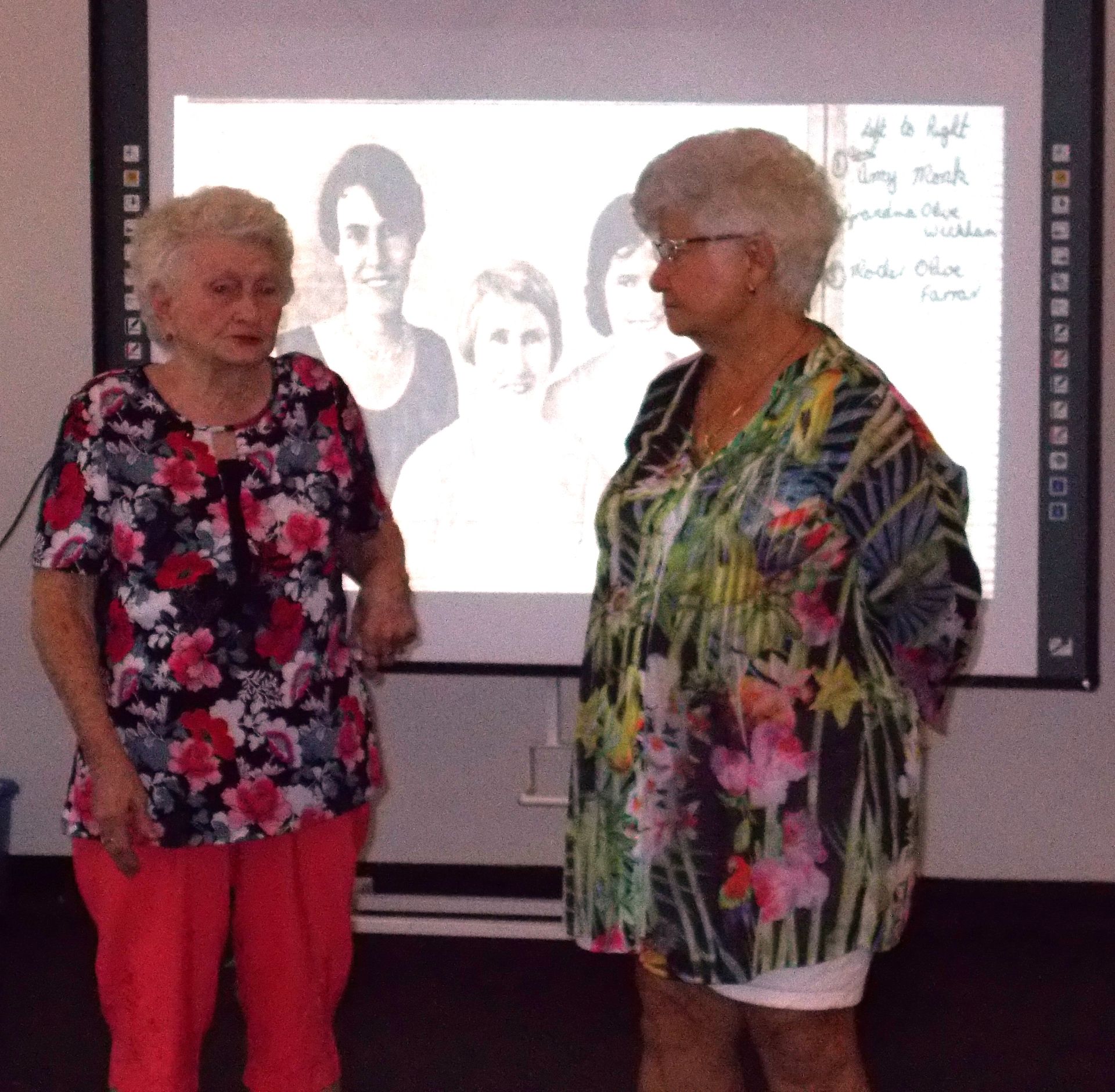Two women standing in front of a projector screen that says ' i am a light ' on it