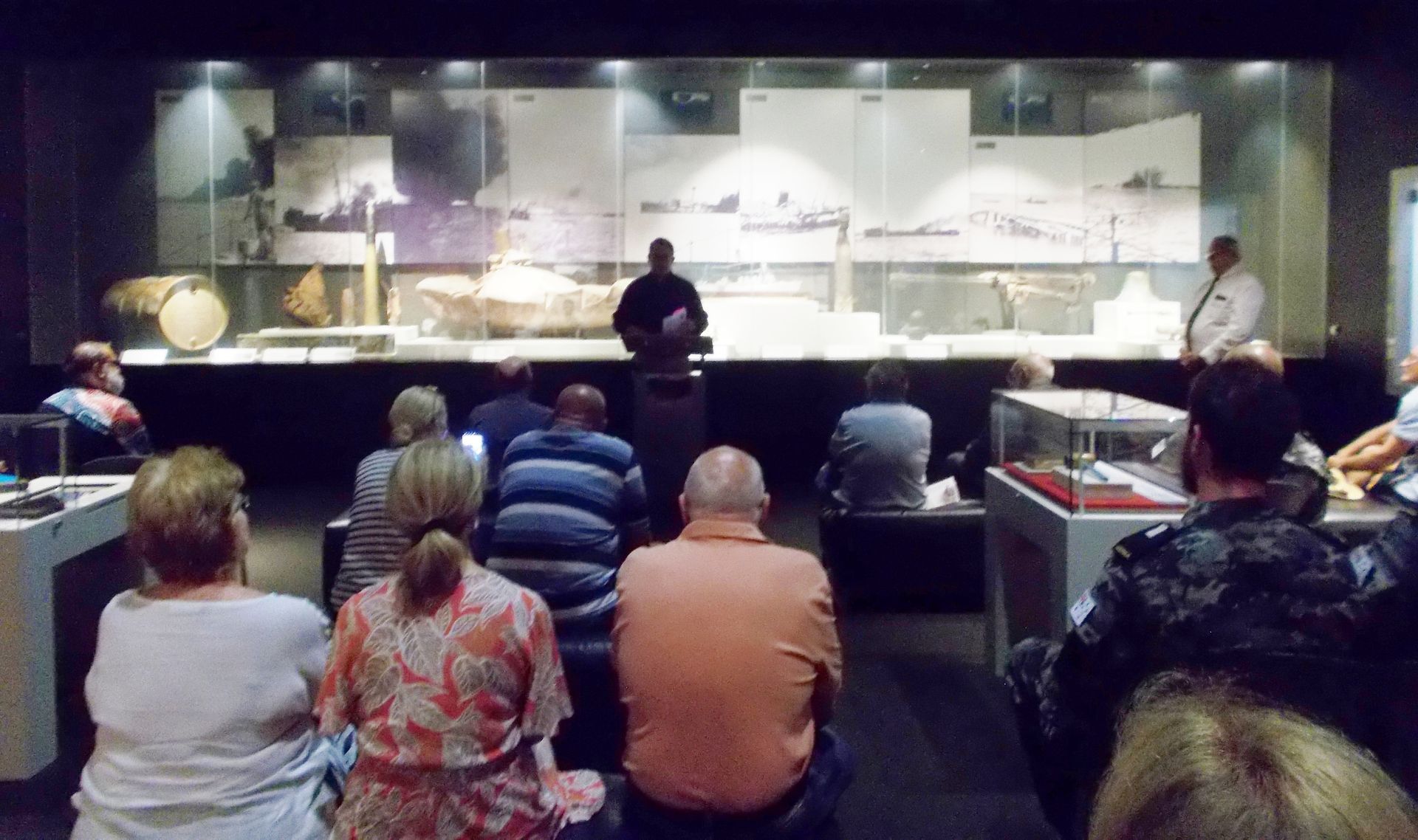 A group of people are sitting in a dark room watching a presentation