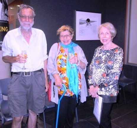 Three people standing in front of a sign that says king